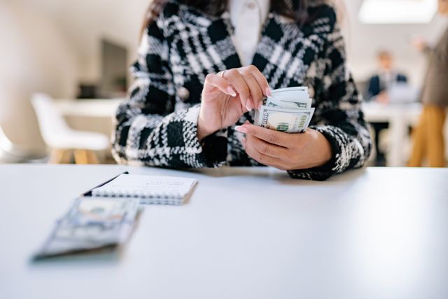 a person counting cash at a desk